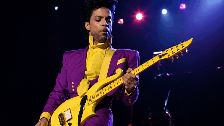Prince performs in a bold purple suit while playing a bright yellow custom Cloud electric guitar.