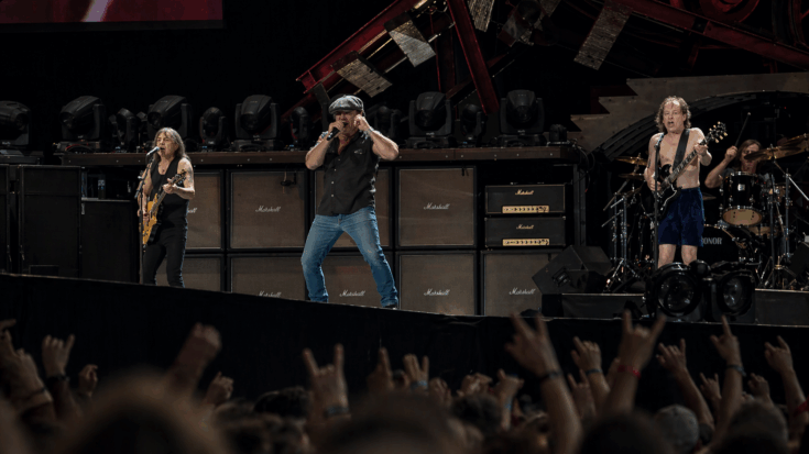 AC/DC performs onstage, with Angus Young playing his signature black Gibson SG electric guitar.