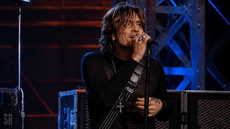 Tommy Lee commands the stage with wild energy, delivering a fierce rock performance under dramatic concert lights.