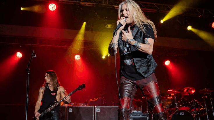 Sebastian Bach belts into the microphone onstage, commanding the crowd under blazing red concert lights.