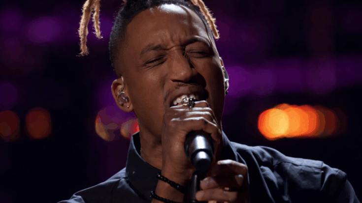 Renzo sings with intense emotion into a microphone, eyes closed under glowing purple stage lights.