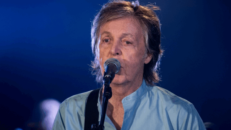 Paul McCartney is depicted in a close-up performance shot, singing into a microphone against a deep blue, atmospheric background.