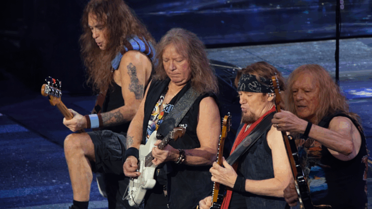 Iron Maiden’s members stand shoulder to shoulder onstage, locked into a powerful live performance.