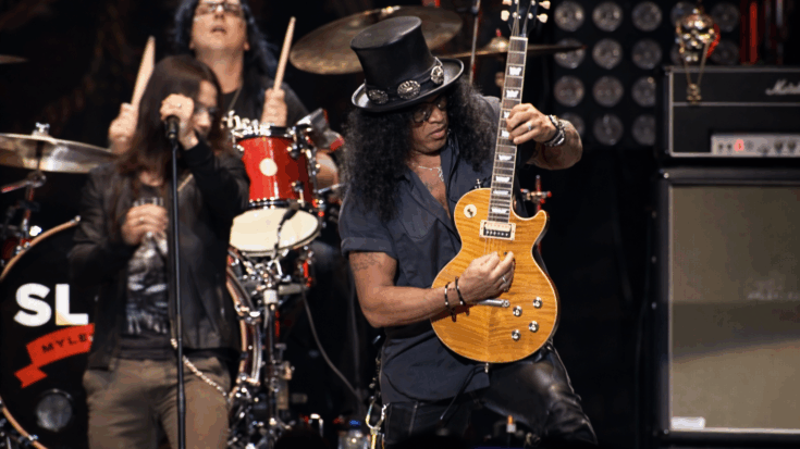Slash rips into a solo onstage with his gold Les Paul and signature top hat.