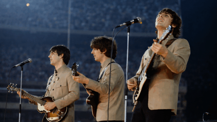 The Beatles perform live onstage, harmonizing and playing their instruments in front of a large crowd.
