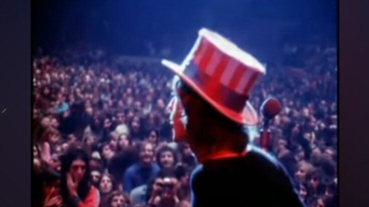 mick Jagger playing on stage with an american hat